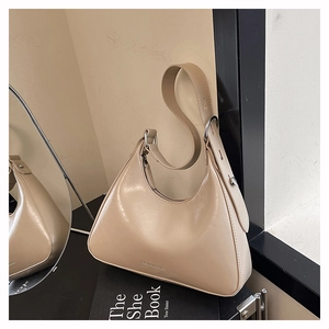 Detail of cream baguette shoulder bag featuring fashion text print and silver hardware