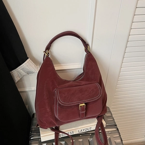 Close-up of burgundy hobo shoulder bag with contrast white stitching and metal buckle pocket