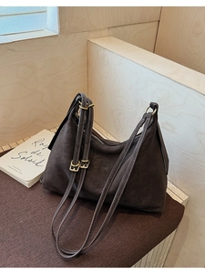 Detail of dark brown matte leather tote with white stitching and gold hardware