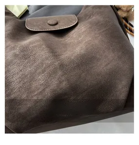 Vue détaillée de la texture du cuir synthétique vintage marron foncé et du bouton pression rond