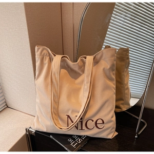 Detailed close-up of beige corduroy tote bag with brown Nice embroidery and dual handles