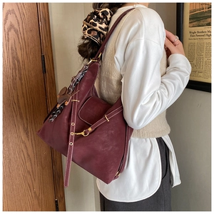 Detail of burgundy large hobo bag with contrast stitching and leather tassels