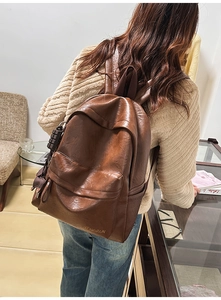 Détails d'un sac à dos vintage en cuir marron foncé avec bretelles et jolis pendentifs