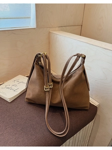 Detail of vintage brown suede tote bag with adjustable straps and gold metal buckles