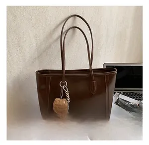 Détail d'un grand cabas en cuir marron foncé avec un charmant porte-clés chien peluche