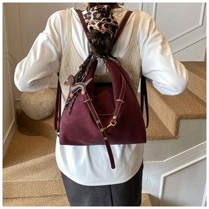 Detail view of burgundy convertible backpack with white contrast stitching and puppy charm