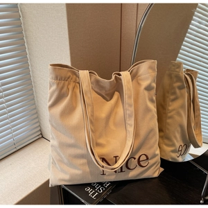 Detail of beige corduroy tote bag featuring brown Nice embroidery and ribbed texture