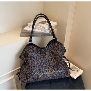 Detail of leopard print tote bag featuring black leather straps and side drawstrings