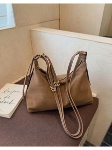 Close-up of vintage brown suede tote bag with contrast stitching and gold buckle detail
