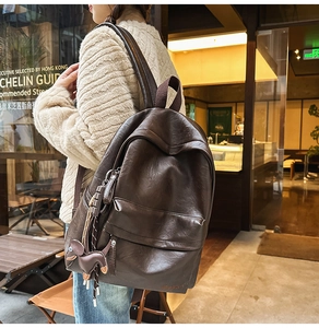 Détail d'un sac à dos vintage en cuir marron foncé avec un joli pendentif de cheval