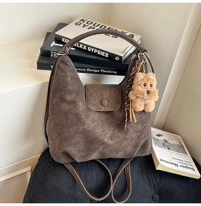 Close-up of retro brown faux leather tote bag with plush puppy pendant and magnetic flap