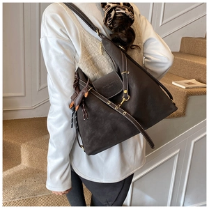Detailed close-up of dark brown faux leather tote bag with branded embossing and metal clasp