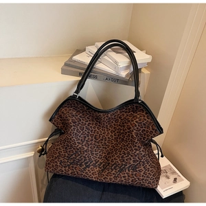 Detail of leopard print tote bag featuring black script embroidery and drawstrings
