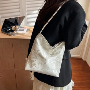 White butterfly print tote bag with braided straps worn over a black blazer for office style