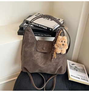 Detail of vintage coffee brown suede tote bag with flap lock and cute plush bear charm