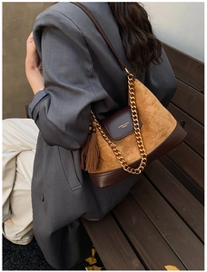 Détail du sac vintage en daim matelassé avec chaîne dorée et accent de pompon en cuir