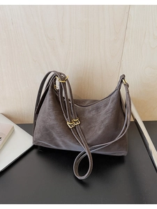 Detailed macro view of dark leather tote bag with gold zipper and textured matte finish