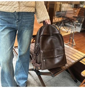 Détail d'un sac à dos en cuir marron foncé avec pendentif cheval dans un café