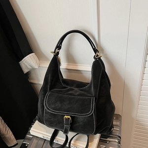 Detail of black PU tote bag featuring white contrast stitching and a gold buckle pocket
