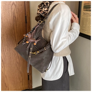 Detail of dark brown leather hobo bag with contrast stitching and dachshund charm