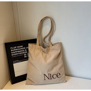 Detail shot of the ribbed corduroy texture and Nice embroidery on the beige tote bag
