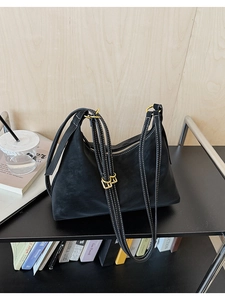 Close-up of black hobo bag with white contrast stitching and gold zipper details