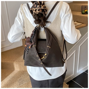 Detail of dark brown matte backpack with white stitching and decorative horse charm