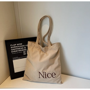 Detail of the soft beige corduroy fabric texture and red Nice embroidery on the tote bag