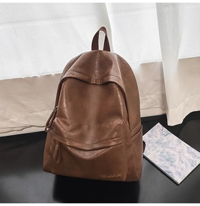 Détail d'un sac à dos rétro en cuir marron foncé avec fermeture éclair et logo imprimé