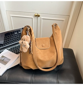 Close-up of caramel vintage tote bag with plush bear charm and matte texture detail