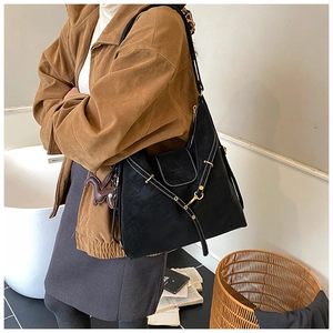 Detail view of black matte leather tote with white stitching and horse charm