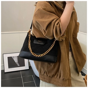 Detail of black suede patchwork shoulder bag with chunky gold chain and logo