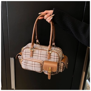 Vue détaillée de la texture du tissu écossais vintage et des accents en cuir du sac