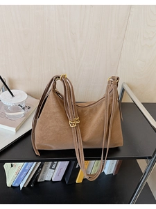 Close-up of dark brown faux suede tote bag with golden hardware and adjustable straps