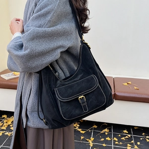 Detailed side view of a black hobo bag with contrast stitching and golden buckle pocket