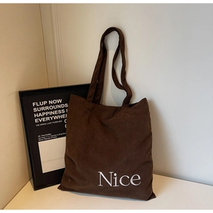 Detail of coffee corduroy tote bag featuring white Nice embroidery and ribbed texture