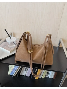 Detail of brown faux leather tote with white contrast stitching and golden buckles