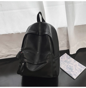 Détail d'un sac à dos noir en similicuir avec texture grainée et poche à zip à pompon