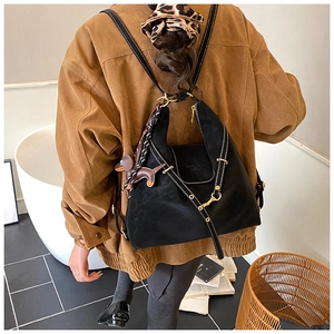Detail of a black suede backpack with white stitching and a dachshund leather pendant