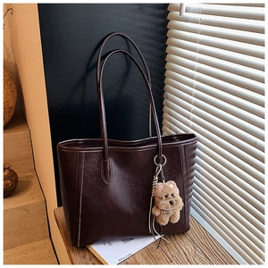 Detailed view of the dark brown leather tote bag with a cute plush dog pendant