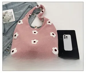 Detail showing pink plush tote bag with white daisy pattern and magnetic metal closure