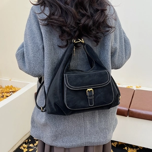 Detail of black vintage hobo bag with contrast stitching and golden hardware on a model