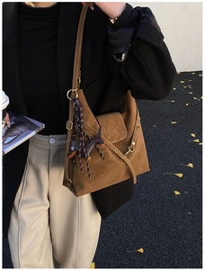 Close-up of vintage brown leather shoulder bag with horse charm on autumn street