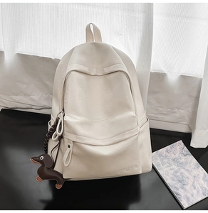 Détail du sac à dos minimaliste en cuir PU crème avec un porte-clé décoratif de teckel
