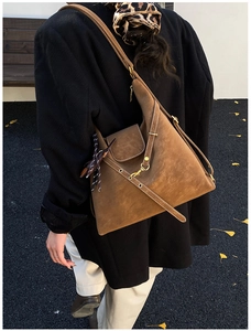 Close-up of retro brown suede tote bag with printed silk scarf on black wool coat