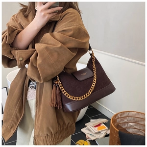 Détail du sac en daim marron foncé avec chaîne dorée et longues franges à glands