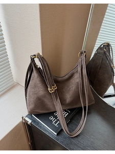 Detail of coffee brown suede tote bag with contrast stitching and golden buckles