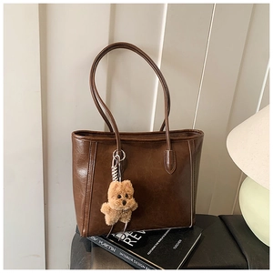 Detail of dark coffee tote bag in glossy leather with a cute plush dog pendant