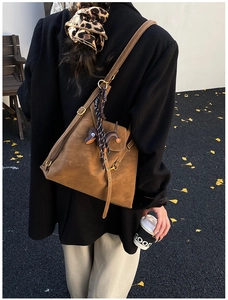 Detail of caramel leather shoulder bag with cute dachshund charm on female model