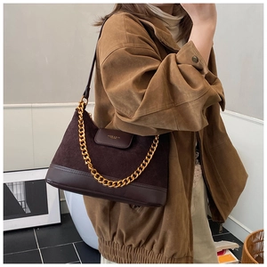 Détail du sac sous le bras en daim marron foncé matelassé avec chaîne dorée